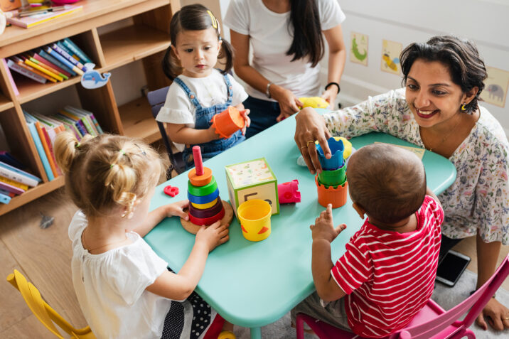 Nursery children playing with teacher in the classroom