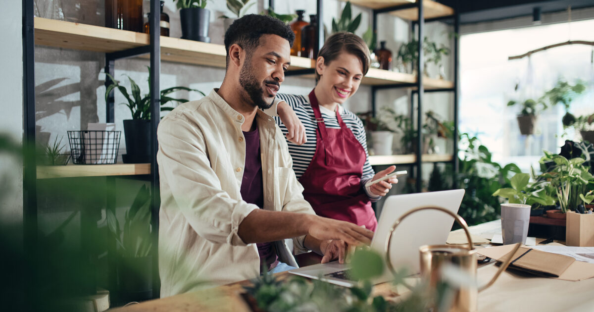 Shop assistants with laptop working in plant store.