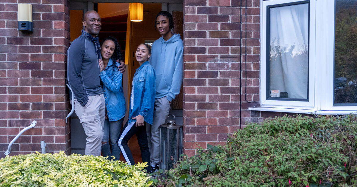 Portrait of family with daughter and son in front of a home.