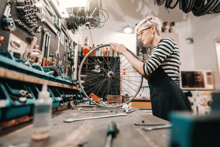 An individual is inspecting a bike rim in a bike shop.